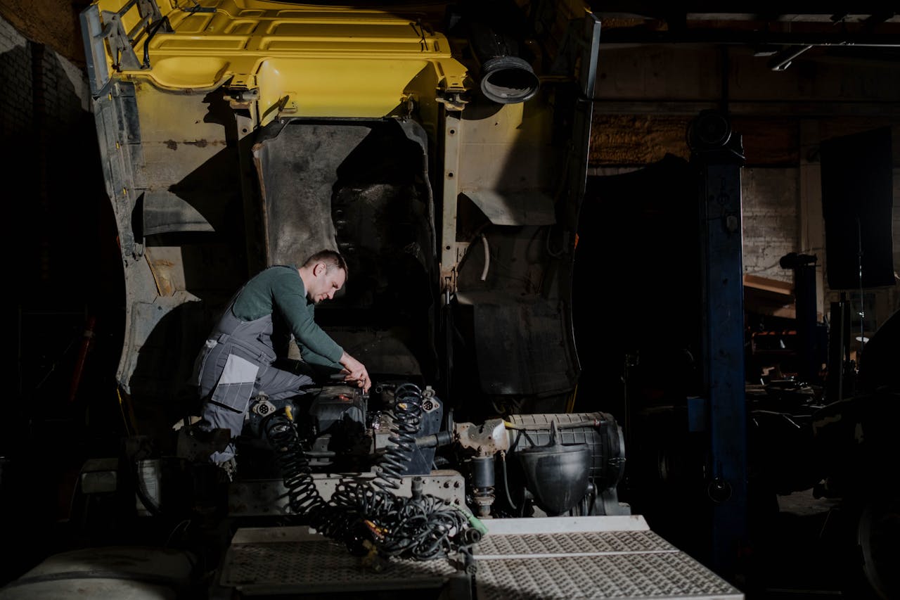 Mechanic inspecting engine in dimly lit garage. Industrial setting with repair focus.